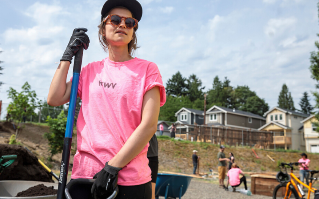 Student holding a shovel looking out at project site