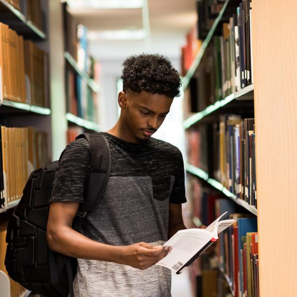 Black male student looks at book in the library
