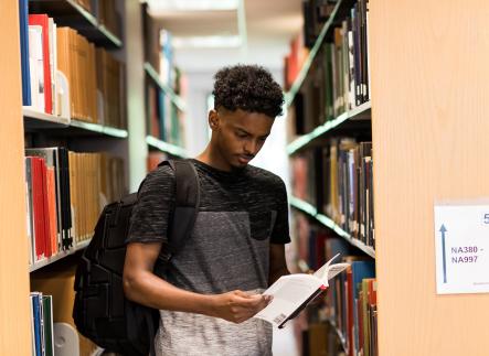 Black male student looks at book in the library