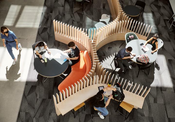 Aerial view of students with face masks studying in FMH lounge.