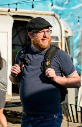 Student with beard and glasses walking near food trucks