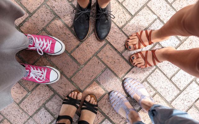 Aerial view of the feet of five people standing in a small circle.