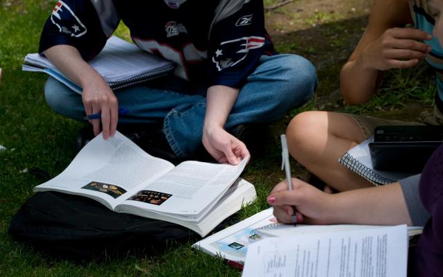 Two students reading books on the grass
