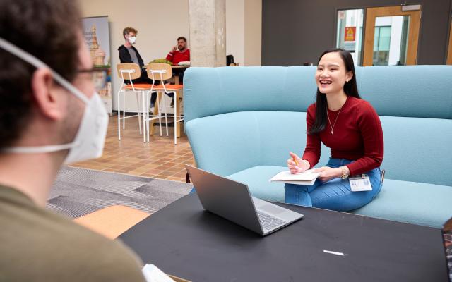 Young woman on laptop talking with someone in a mask