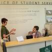 Two people, one standing and one sitting, behind a reception desk