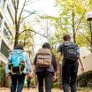 Three students in backpacks walking down the park blocks.