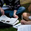 Two students reading books on the grass