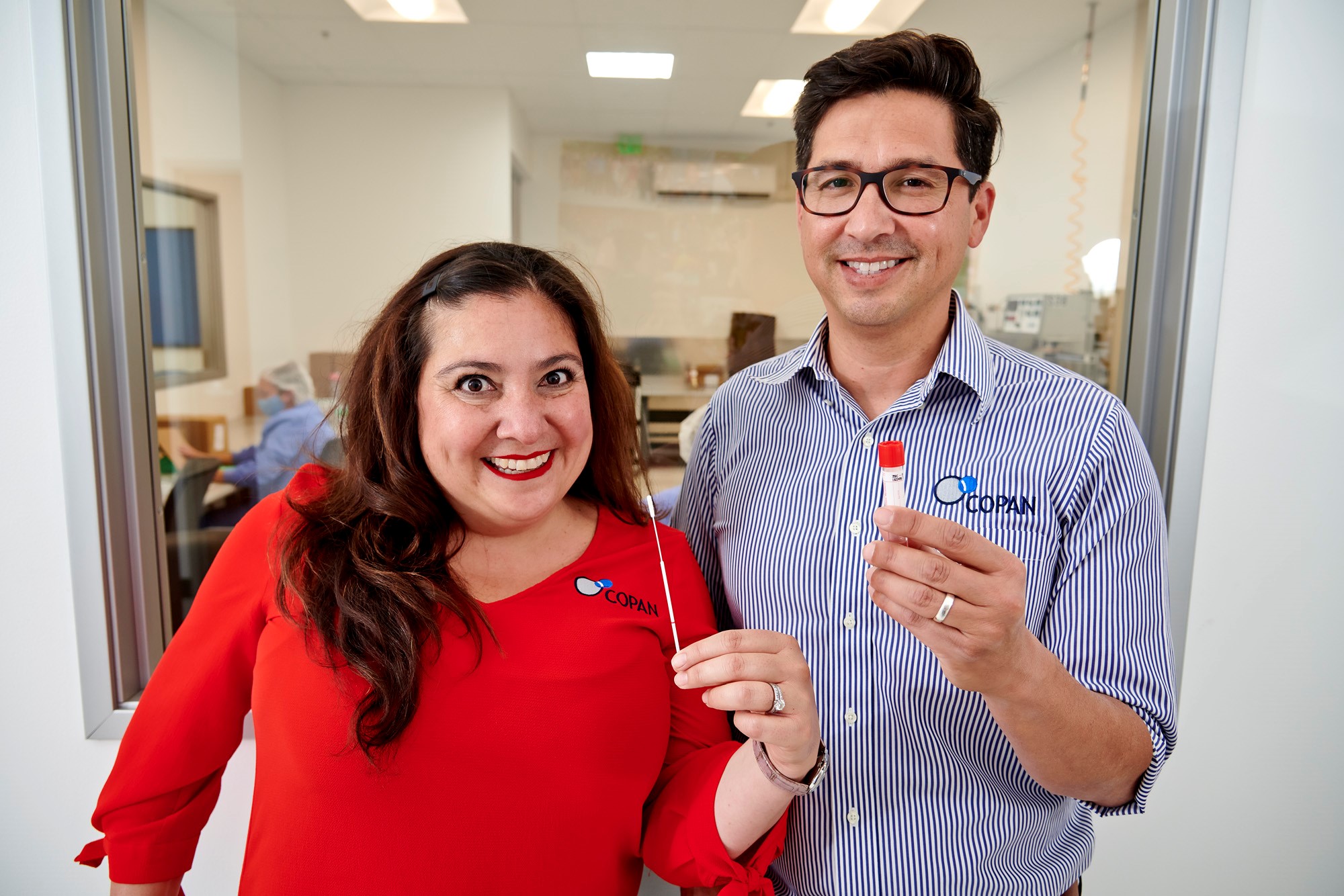 Gabriela and Franco holding up a COVID-19 testing swab kit