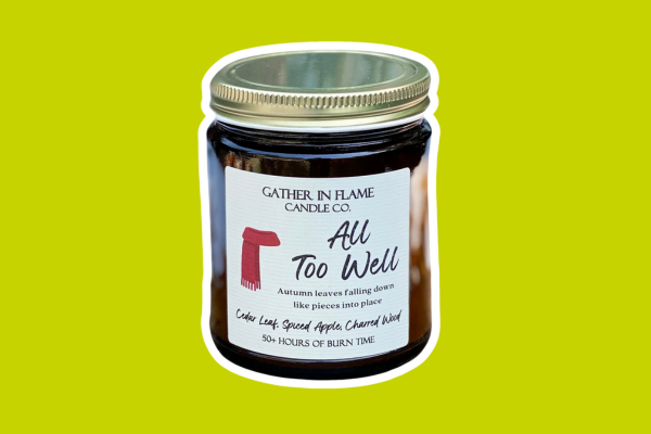 Candle in a jar with the name "All too well" and a red scarf on the label.