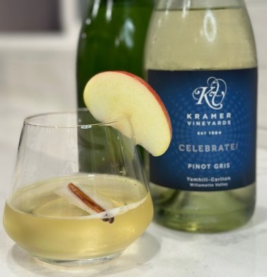 Apple cider and wine mimosa in a glass next to two bottles of wine.