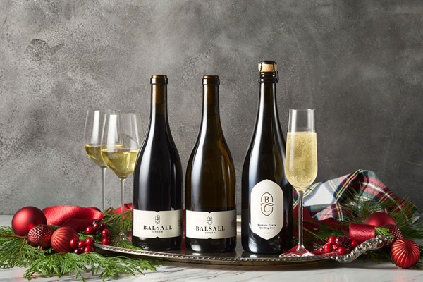 Three Balsall Creek wine bottles with three glass es and holiday decor surrounding.