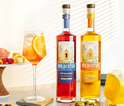 Two bottles of Wilderton Aperitivo next to a glass with a cocktail in it.