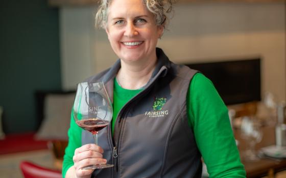 Meara McNally Butler from Fairsing Vineyard posing holding a glass of wine.