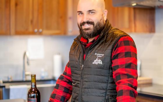 Tommy Miller from Pomeroy Cellars posing with a bottle of his wine.
