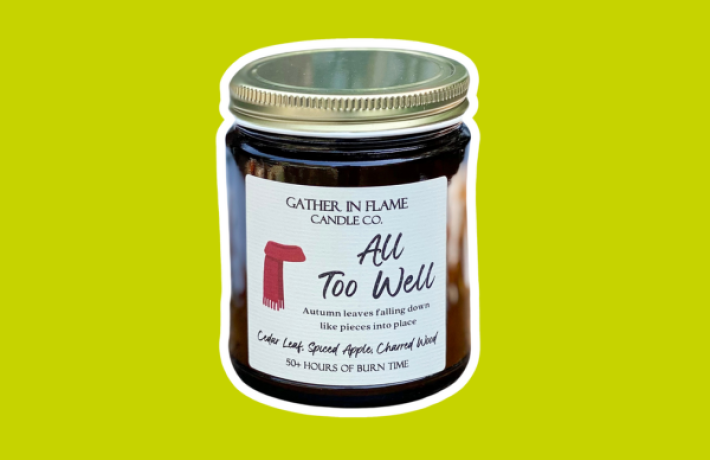 Candle in a jar with the name "All too well" and a red scarf on the label.