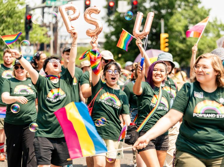 Group of alumni and students waving in excitement as they are marching together at the Pride Parade