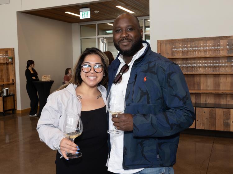 Two guests holding wine tasting glasses at the winemaker's tasting event.