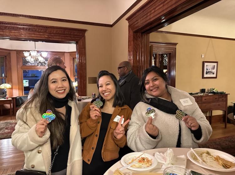 Three alumni business owners at a networking event holding up PSU stickers.