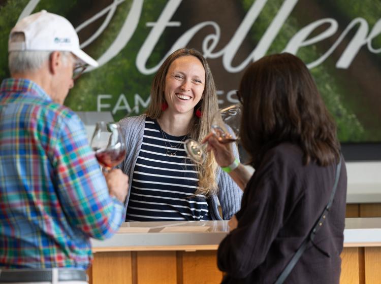 Kim Bellingar, alum and owner of Bellingar Estates sharing a smile who two attendees sample her wine.