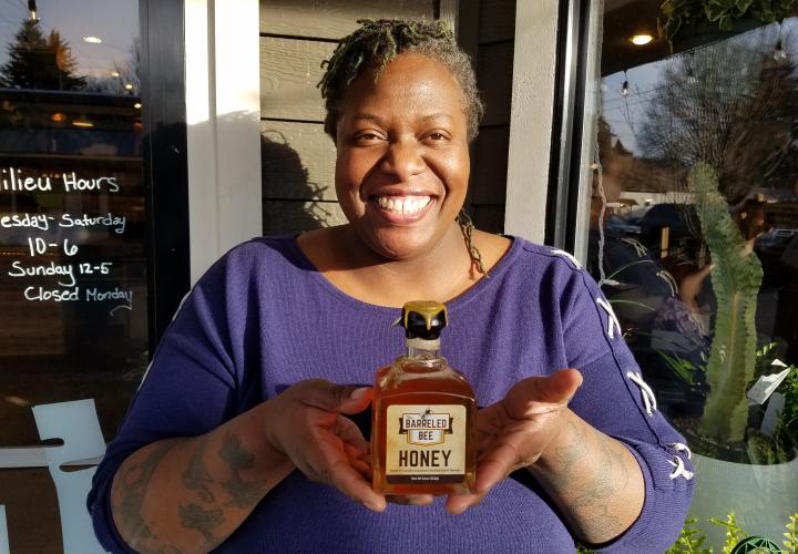 alumna Lee Hedgmon holding her barrel-aged honey bottle