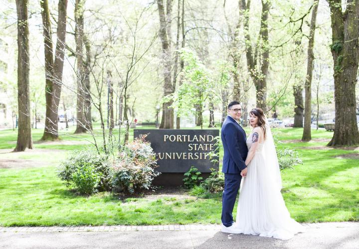 Bride and groom posing in front of the Portland State University sign in the Park Blocks