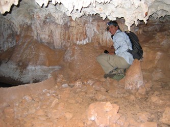man below stalactites in cave