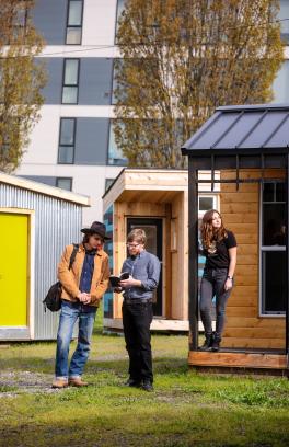 Students and faculty stand together among sleeping pods designed and built by CPID students