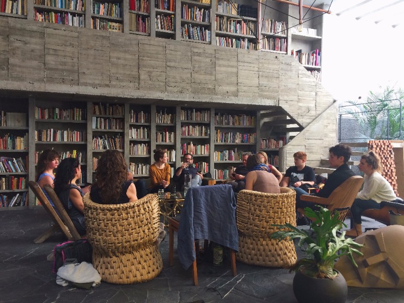 Group of students seated in a circle, talking with artist Pedro Reyes