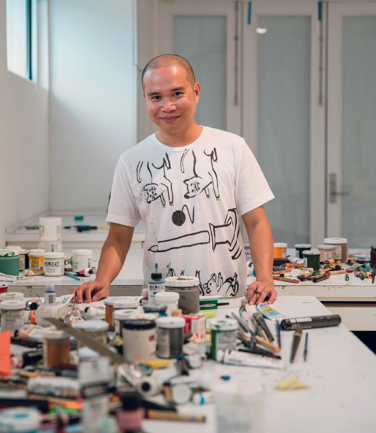 Ralph Pugay in his studio surrounded by paint cans and other art supplies.