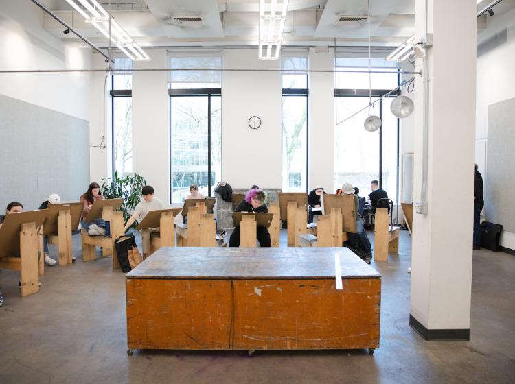 Drawing studio with students seated on drawing horses, working on drawing boards