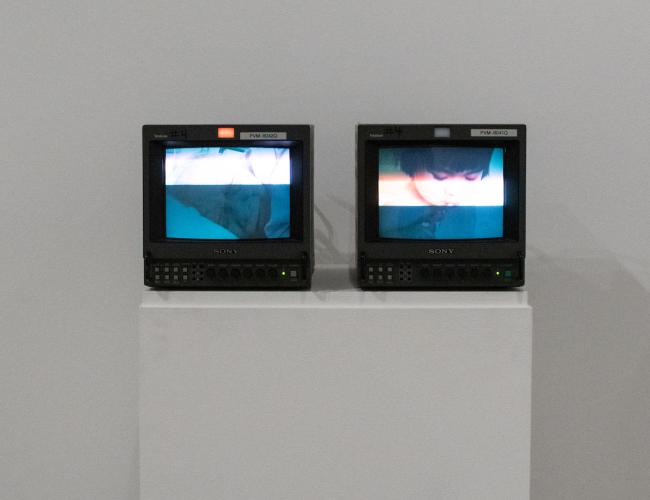 Two video monitors, side-by-side, display a series of images of the artists and her grandmother.