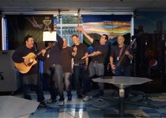 Six men, two with guitars, perform a comedy sketch at CRCI.
