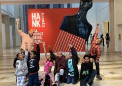 Stevenson and a group of King School students pose with fists raised in front of a sculpture by Hank Willis Thomas at the Portland Art Museum.
