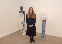 Johanna Houska standing in the gallery next to her work.