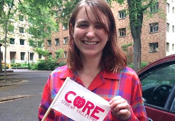 Student at a Core event, holding a small flag that says Core Student Collective