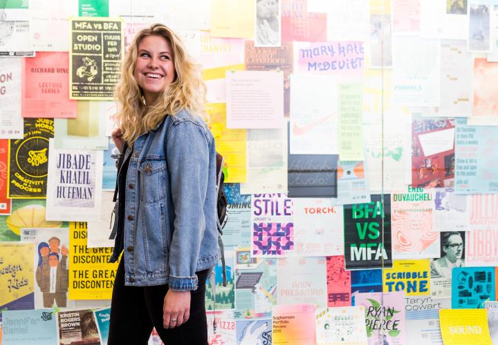 Woman viewing a display of posters made by graphic design students