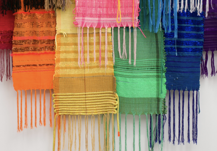 Collection of woven textile pieces, each a different color of the rainbow.