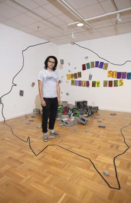 Art practice student standing in his art installation at the Littman Gallery