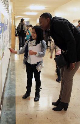 A young girl docent points to an artwork as she explains its significance to a visitor