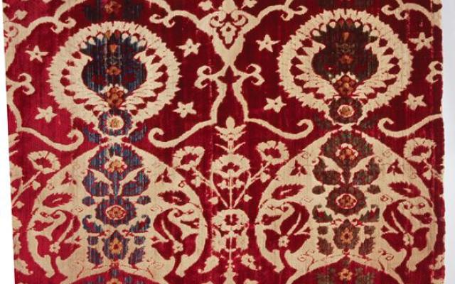 Detail of liturgical robe with ornate floral decoration in red and beige.