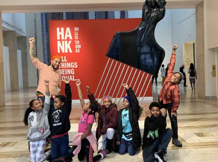 Stevenson and a group of King School students pose with fists raised in front of a sculpture by Hank Willis Thomas at the Portland Art Museum.