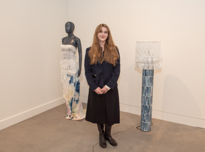 Johanna Houska standing in the gallery next to her work.