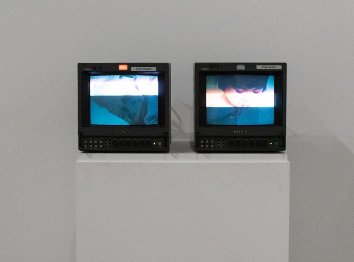 Two video monitors, side-by-side, display a series of images of the artists and her grandmother.