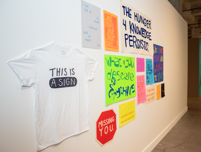 Installation of colorful signs and banners arranged on a gallery wall.