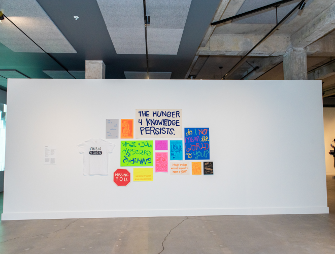 Arrangement of colorful signs and banners on a gallery wall.