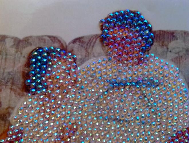 Vintage photo of a woman and child on a sofa. The two figures are obscured by a layer iridescent rhinestones.