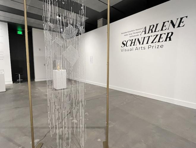 Installation view of crystal bead curtain hanging from a rectangular gold frame.