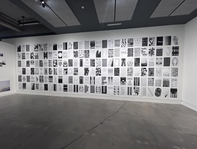 A gallery wall filled floor to ceiling with black and white posters featuring uplifting messages and designs.