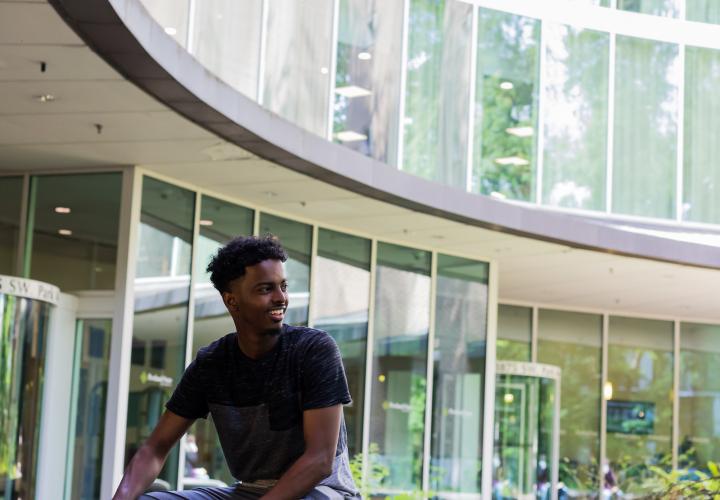 Student sitting on bench outside library with backpack