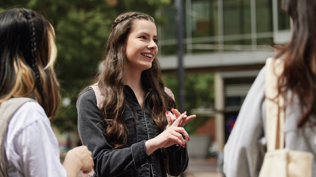 Student discussing with friends in the park blocks.
